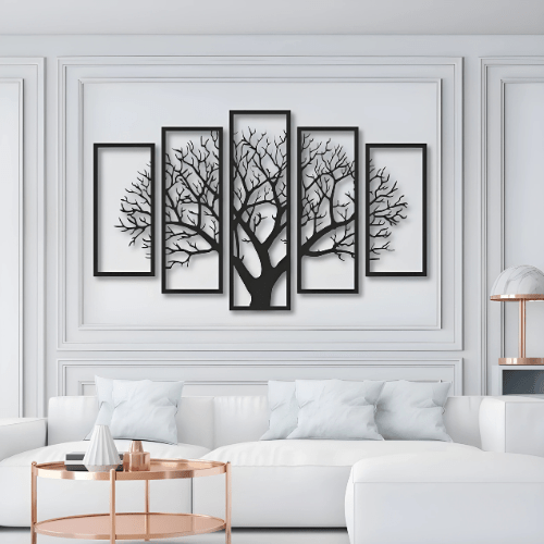 Five framed black tree silhouettes on a white wall above a white sofa.