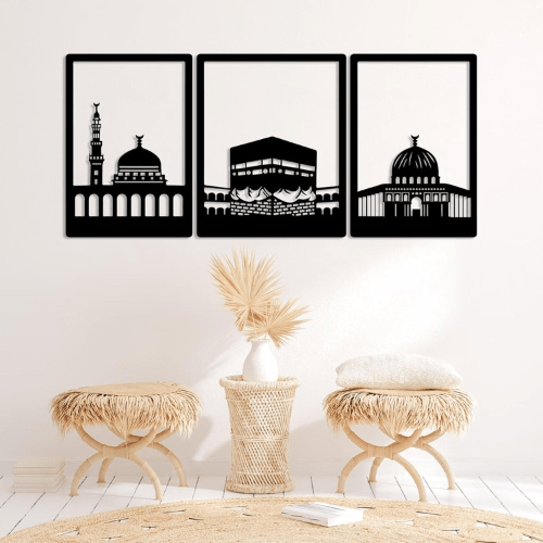 Three black framed artworks of architectural silhouettes on a white wall with decorative stools and a vase.