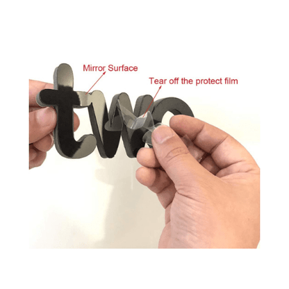 Hand holding a mirror surface decorative letter 'W' with instructions on how to use it.